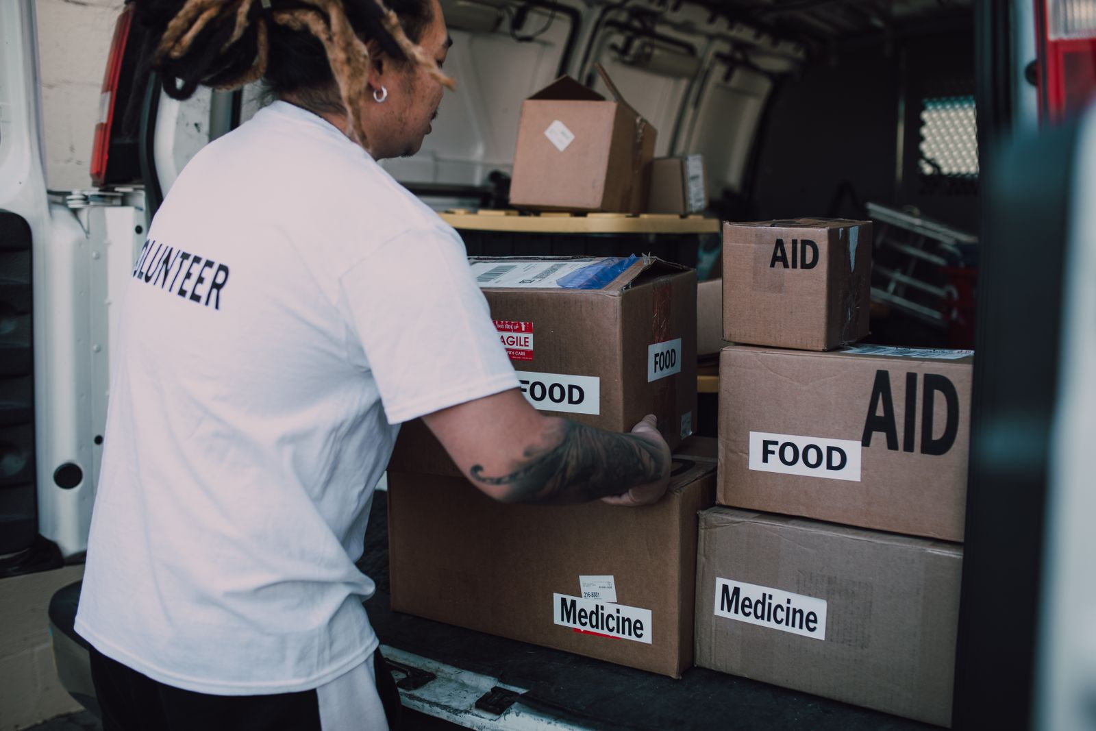 A volunteer loading boxes marked food, medicine, and aid into the back of a van