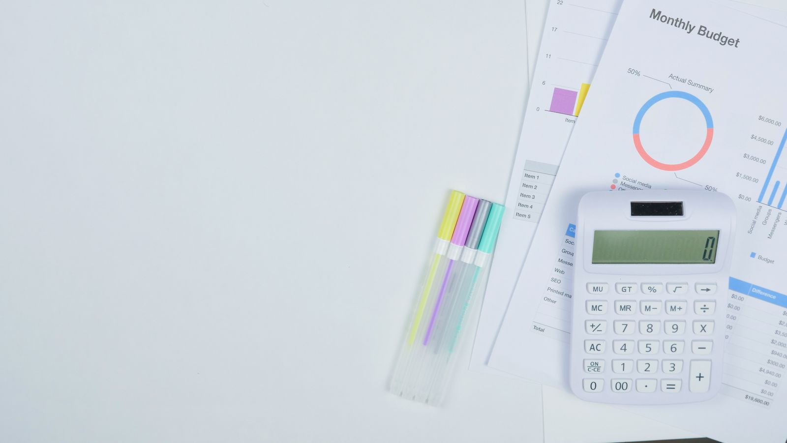 A monthly budget worksheet, calculator, and pens laid out on a desk