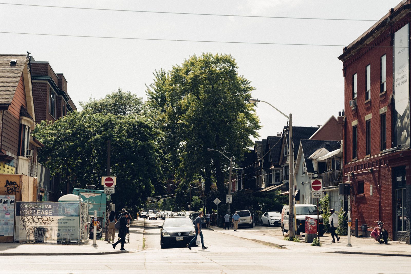 A city street of brick storefronts with people walking
