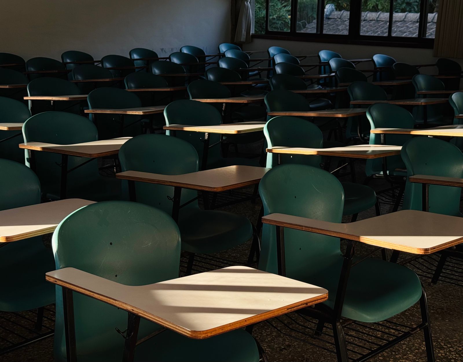 Rows of empty classroom desks with afternoon light across them