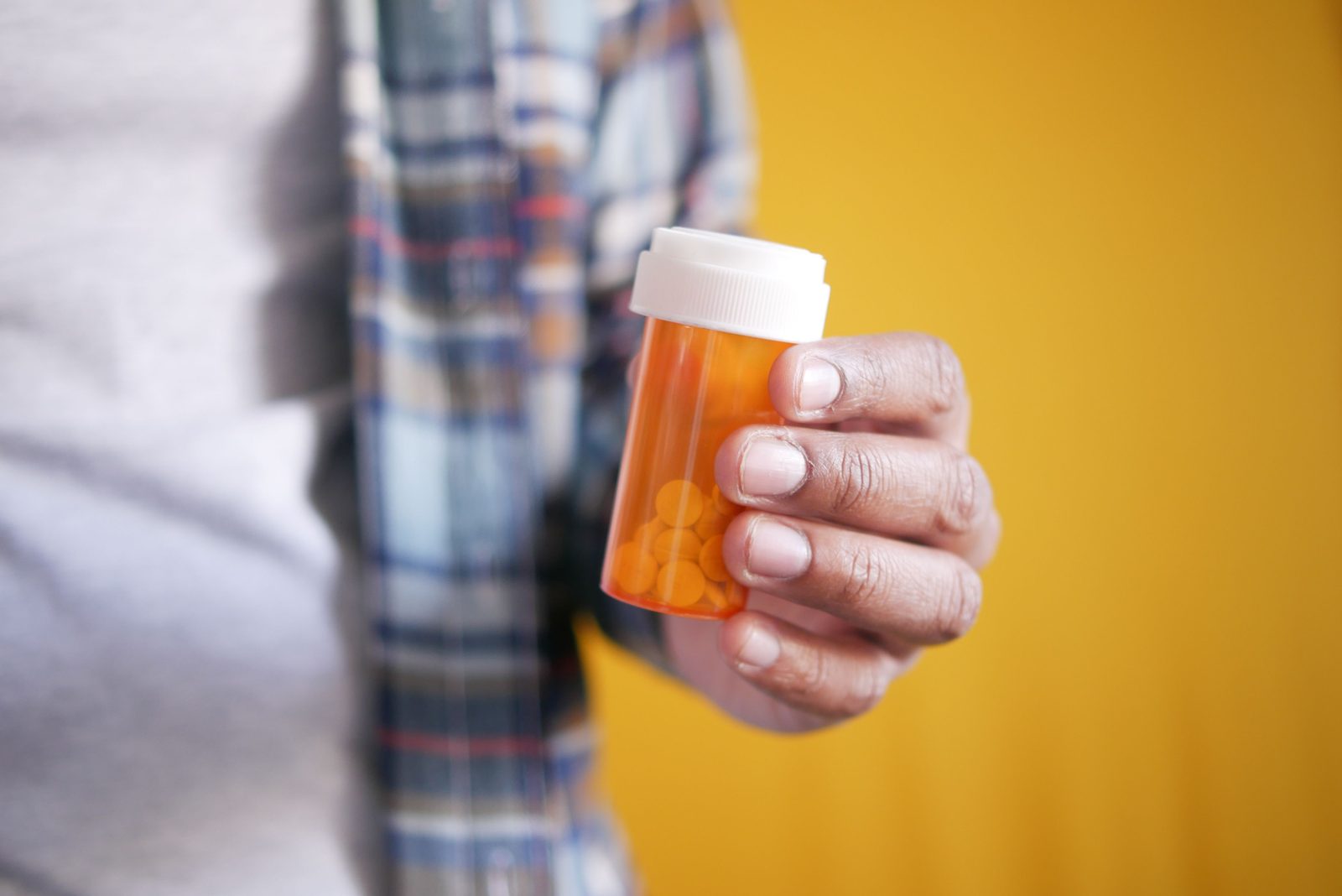 A person holding an amber prescription bottle