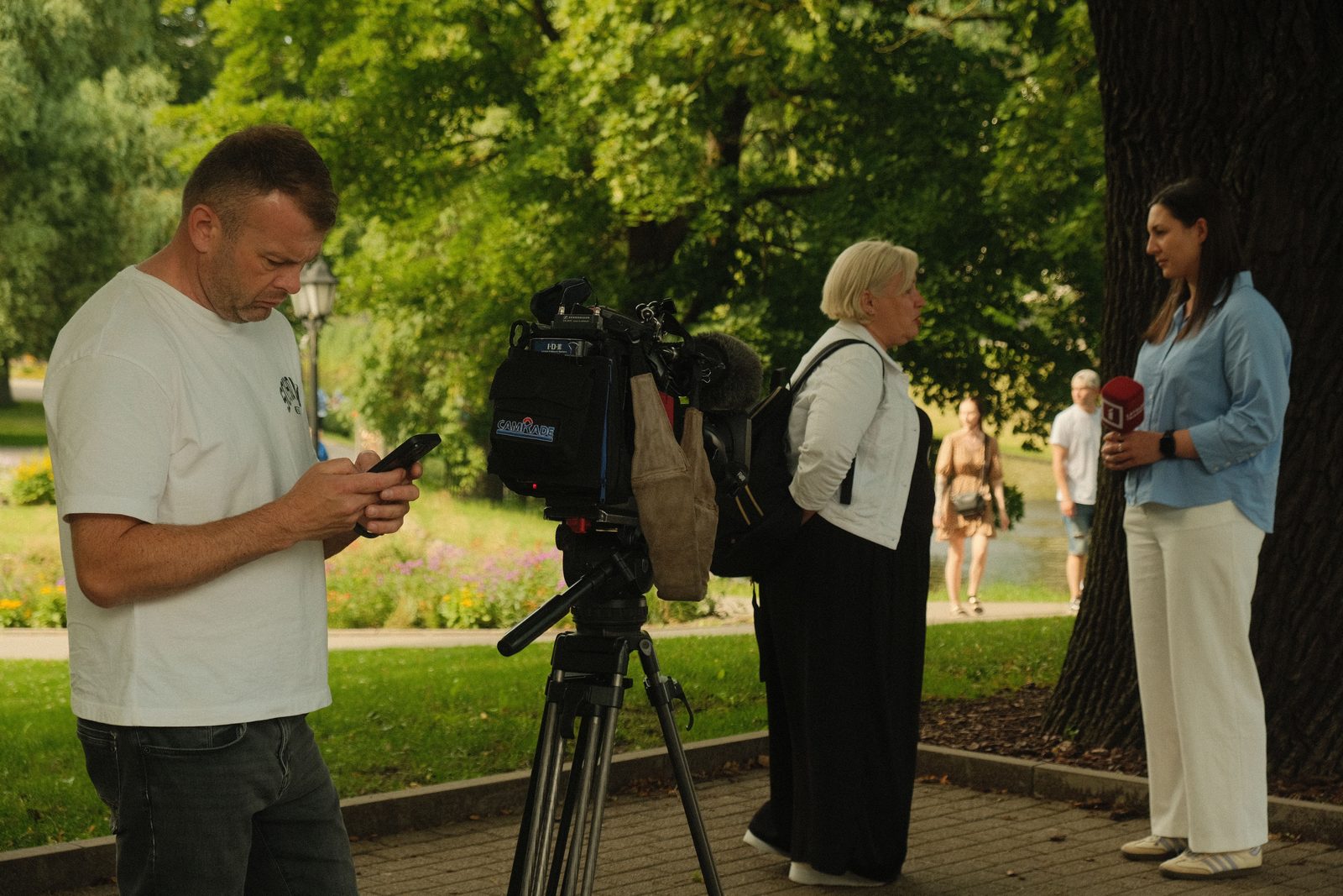 A camera operator filming a reporter interviewing someone outdoors