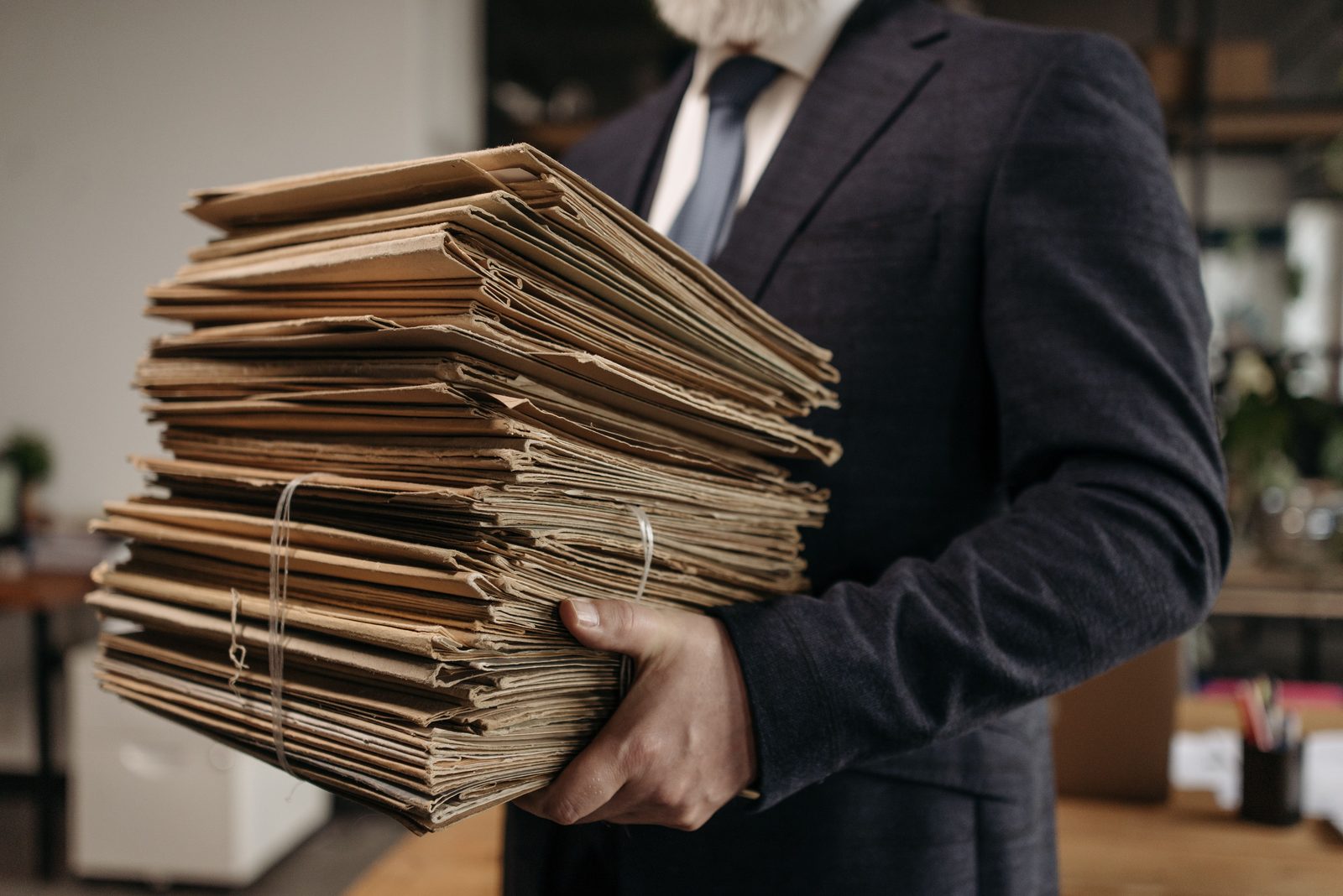 A person carrying a tall stack of document folders