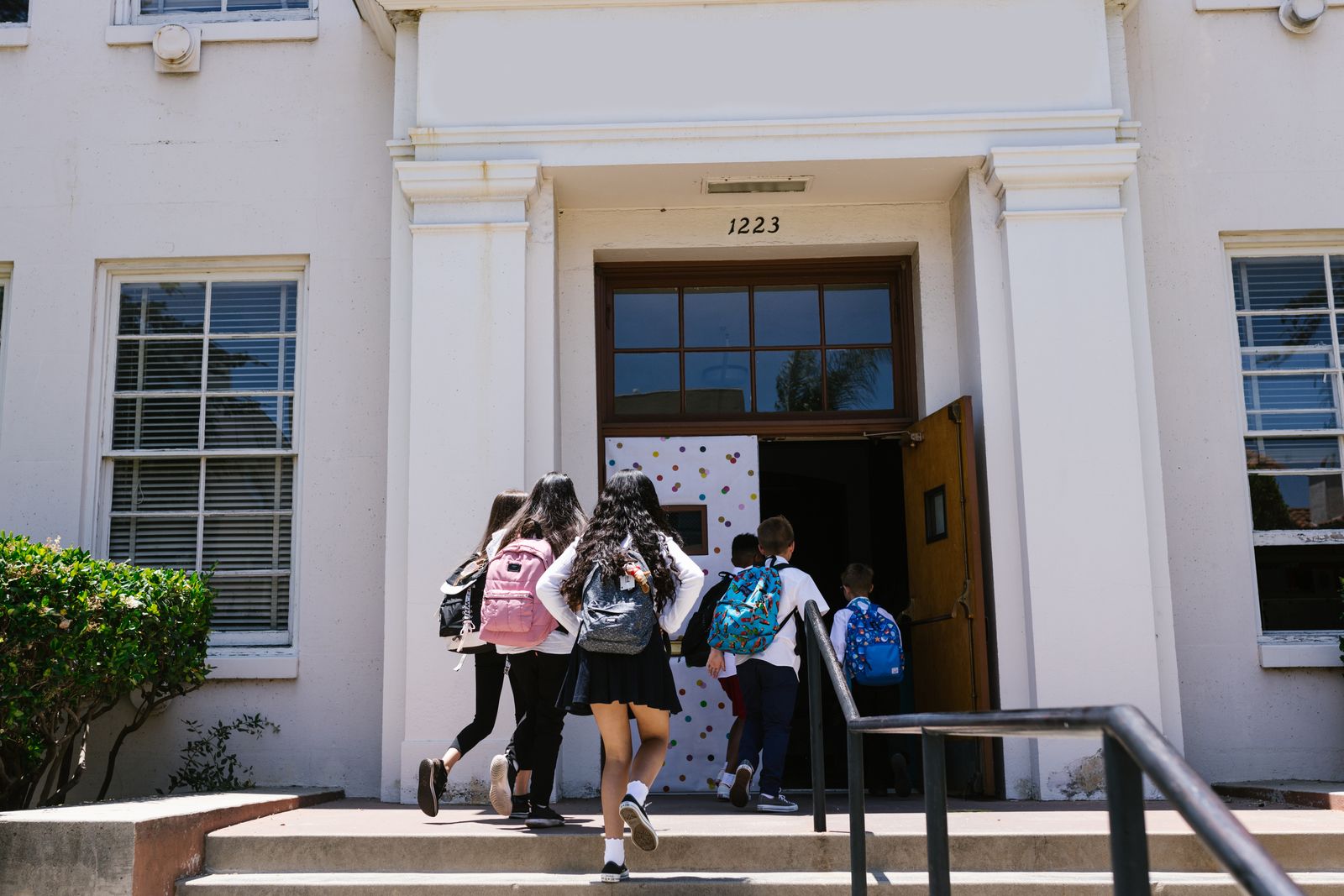 Students with backpacks walking up the steps into a school building