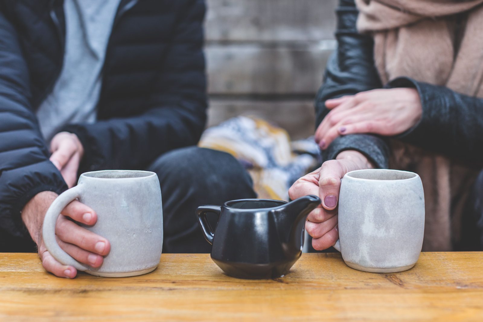 Two people at a table with coffee mugs between them