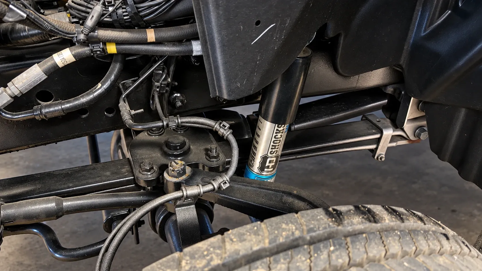 Front suspension of the Frontier All Terrain chassis in the shop, showing a heavy-duty shock absorber, leaf spring and brake lines above the tire
