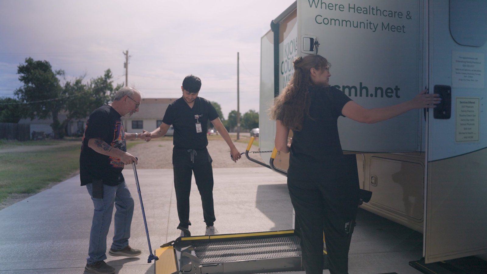 Clinical staff helping a patient onto the wheelchair lift of a rural mobile health clinic